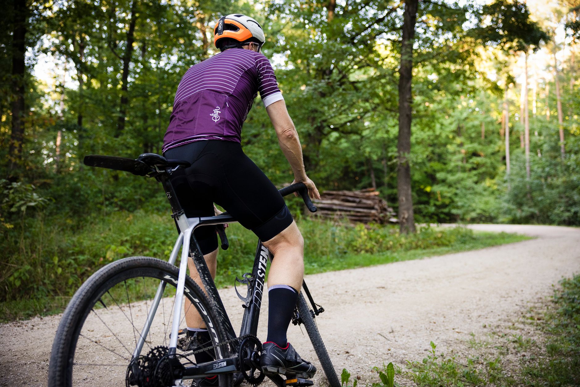 Rowerzysta w kasku jedzie leśną szutrową ścieżką